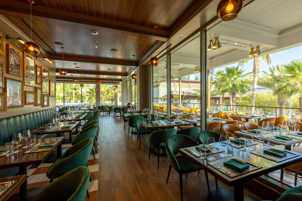 The dining room at Gordon Ramsay at The Carnaby, with green velvet chairs, wood floors, and windows looking out over Downtown Disney District. | CREDIT: Disneyland Resort