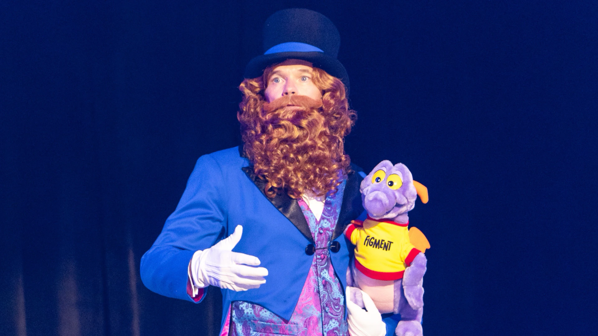 The Dreamfinder character on stage at D23 2026 holding a Figment puppet. | CREDIT: Disney