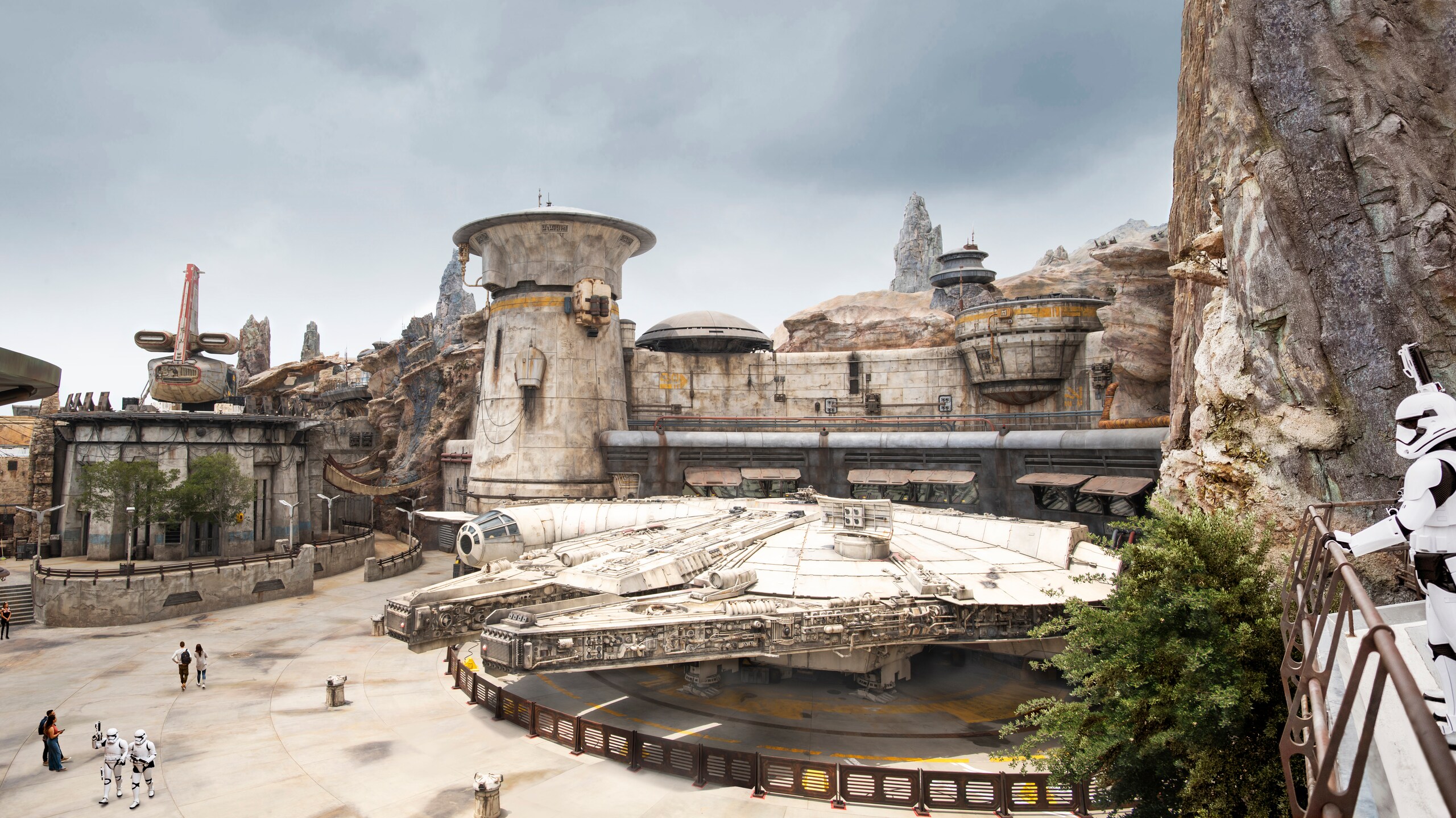 A wide view of Black Spire Outpost in Star Wars: Galaxy's Edge with the Millennium Falcon parked in the courtyard. | CREDIT: Disney