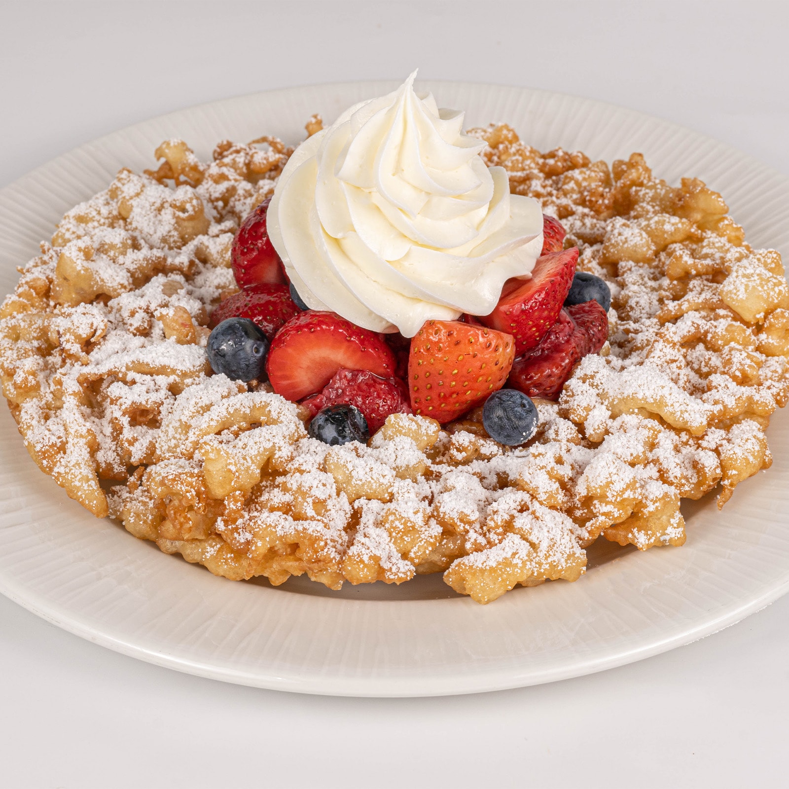 Funnel Cake with Berries, Powdered Sugar, and Whipped Cream